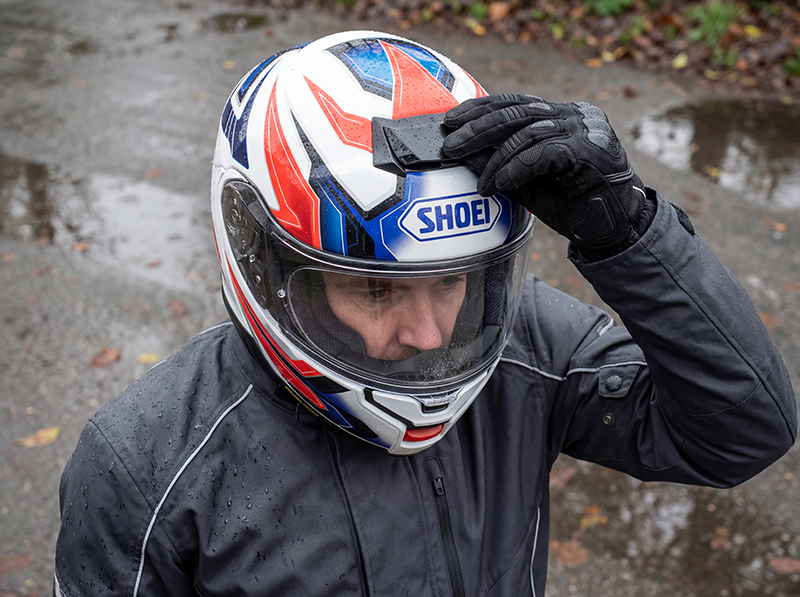 Man-adjusting-vents-on-Shoei-Neotec-3-on-damp-day